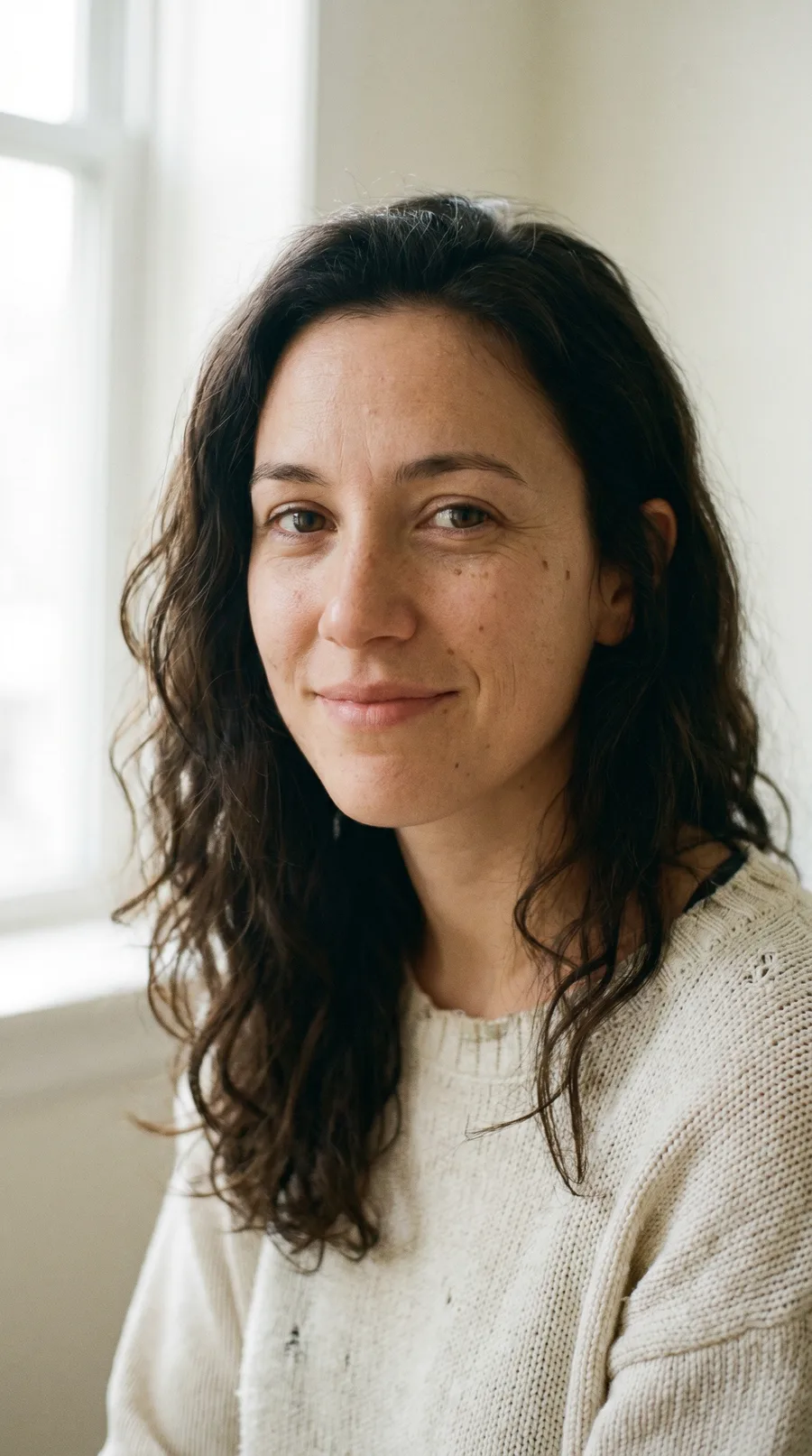 Woman with curly dark hair, natural indoor portrait